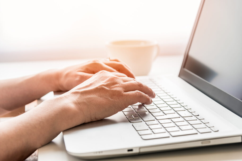 Hands of a woman typing on a laptop